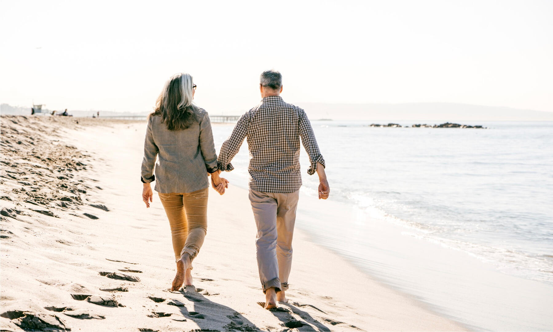 About us Retirement Couple walking on beach